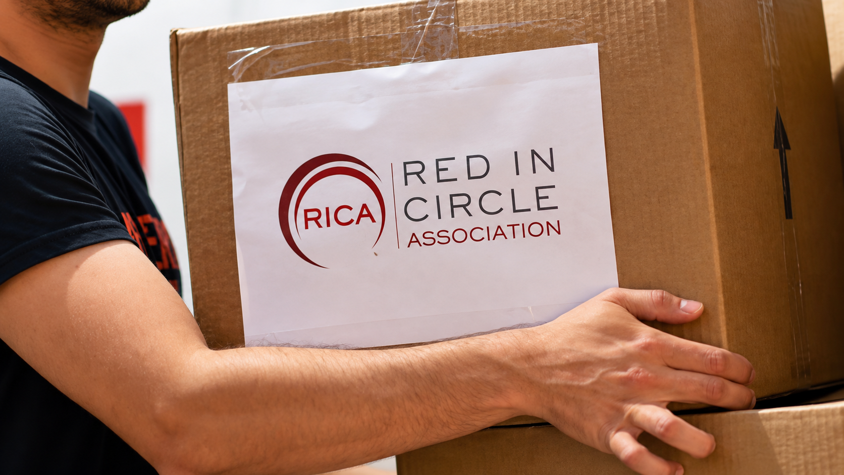 Un bénévole tient un carton portant le logo de Red In Circle.