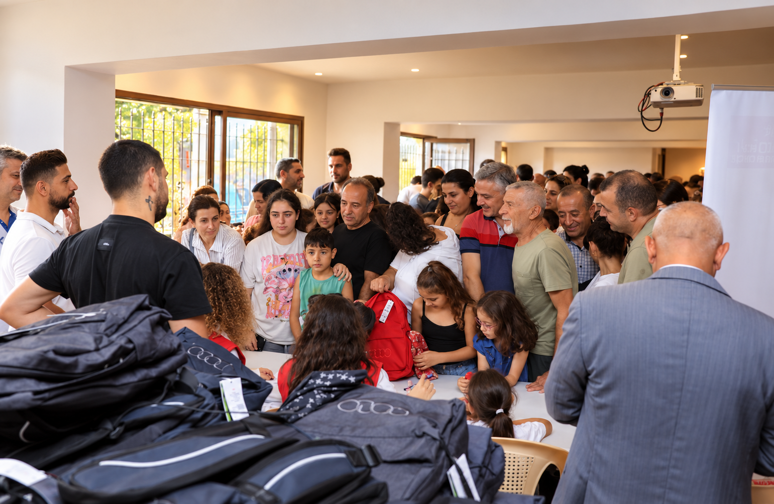 Des adultes et des enfants se réunissent lors d’un événement communautaire au Liban pour recevoir des sacs à dos scolaires et bénéficier du soutien des bénévoles.